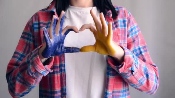 Unrecognizable Girl Painted Hands Blue Yellow Shows Heart Shape Her — ストック動画