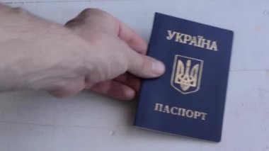 Male hand puts Ukrainian passport on a table. Inscription in Ukrainian Ukraine Passport . Travel or migrants concept.