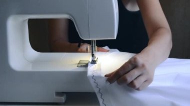 experienced worker works on a sewing machine. hands close up. workshop business concept. female hands sew clothes on a sewing machine. Woman working with fabric and sewing machine