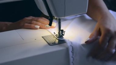 experienced worker works on a sewing machine. hands close up. workshop business concept. female hands sew clothes on a sewing machine. Woman working with fabric and sewing machine
