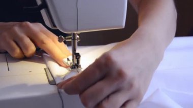 experienced worker works on a sewing machine. hands close up. workshop business concept. female hands sew clothes on a sewing machine. Woman working with fabric and sewing machine