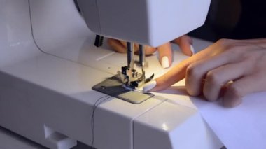 experienced worker works on a sewing machine. hands close up. workshop business concept. female hands sew clothes on a sewing machine. Woman working with fabric and sewing machine