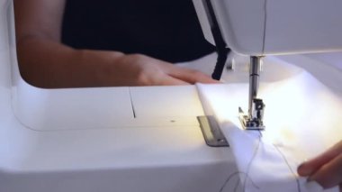 experienced worker works on a sewing machine. hands close up. workshop business concept. female hands sew clothes on a sewing machine. Woman working with fabric and sewing machine