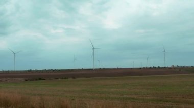Wind turbine spinning over farmers fields at cloudy weather. Green energy concept