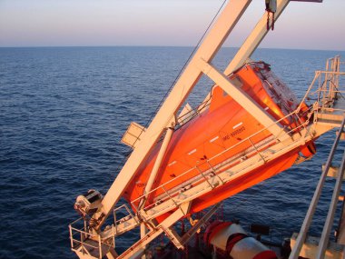 Tamamen kapalı bir cankurtaran botu bir gemiyle beşiğe yerleştirilmiş.