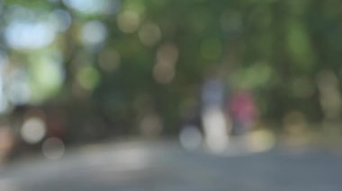 Bulanık yeşil halk parkı, ağaçlar gri yollar insanların yürümesini engelliyor.