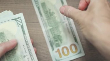 Tahta bir arka planda el sayımı 100 dolar.