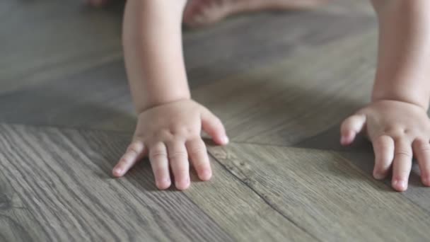 Крихітні маленькі пальці рук кавказького немовляти повзають на дерев'яній підлозі — стокове відео