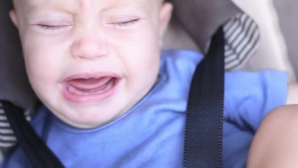 Zbliżenie płacz dziecko niemowlę twarz Duży niebieski oczy siedzi w siedzeniu zapięte pasy — Wideo stockowe