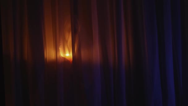 Assustador assustador mulher silhueta com queimando vela se movendo atrás cortina no escuro — Vídeo de Stock