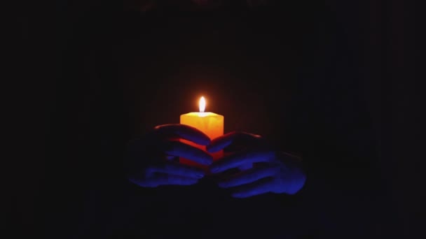 Espeluznante espeluznante manos azules dedos sosteniendo vela amarilla naranja ardiente en la oscuridad — Vídeos de Stock