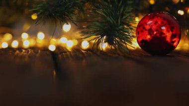 Kırmızı süslemeli cam top yeşil Noel ağacında bulanık ışıklarla asılı.