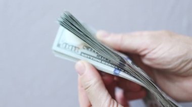 Açık gri arka planda 100 dolarlık banknotları karıştırma
