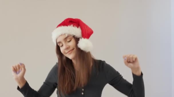 Счастливая молодая брюнетка женщина красный Санта помощник шляпа зеленая одежда серый фон — стоковое видео