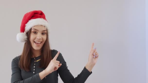 Glad ung brunett kvinnlig röd Santa hjälpare hatt grön kläder grå bakgrund — Stockvideo
