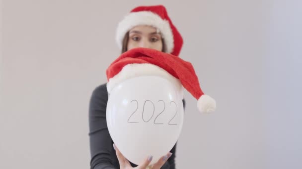 Ung kvinnlig grön skjorta och röd Santa hatt håller vit ballong 2022 siffror — Stockvideo
