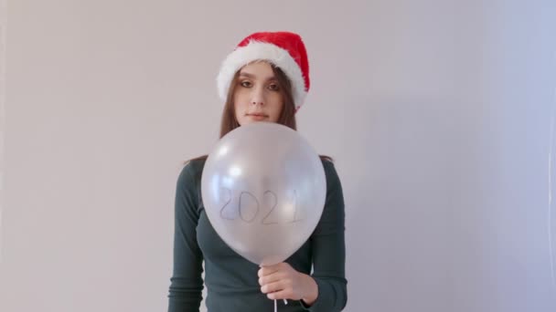 Ung hona grön skjorta och röd Santa hatt håller vit ballong 2021 låt flyga — Stockvideo