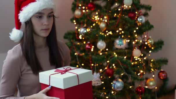 Triste caucásico feliz morena mujer santa sombrero rojo caja de regalo decorado abeto — Vídeos de Stock