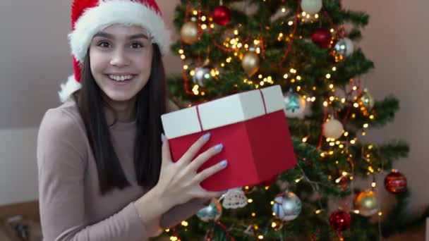 Bonita caucásica feliz morena mujer Santa sombrero rojo caja de regalo decorado abeto — Vídeos de Stock