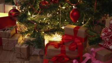 Noel ağacının altında kırmızı el işi hediye kutuları yanıp sönen yılbaşı ışıkları