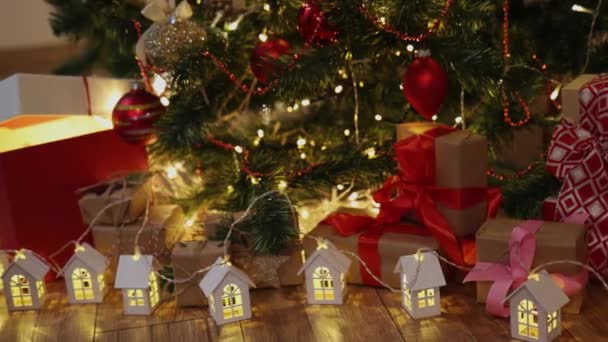 Noel beyaz tahta çelenk evleri. Işıklar köknar ağacı süslemeli kırmızı hediye kutusu. — Stok video