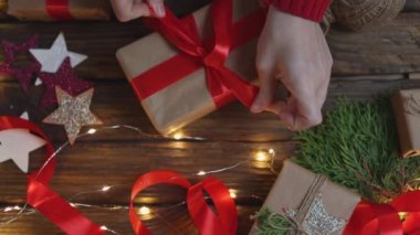 Noel hediyelerini paketleyen kadın elleri kırmızı kurdele bağlayan el sanatları kağıdı