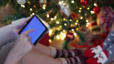 Noel çoraplı kadın süslenmiş köknar ağacı tabletinin altında oturuyor. 