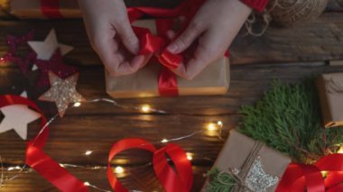 Noel hediyelerini paketleyen kadın elleri kırmızı kurdele bağlayan el sanatları kağıdı
