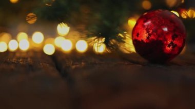 Kırmızı süslemeli cam top yeşil Noel ağacında bulanık ışıklarla asılı.