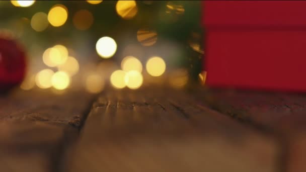 Kotak hadiah merah Karangan bunga pohon Natal defocused lampu kabur latar belakang kayu — Stok Video