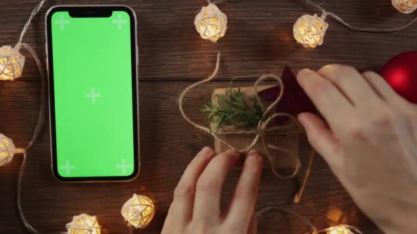 Opakowanie DIY prezent świąteczny smartfon zielony ekran na drewnianym stole — Wideo stockowe