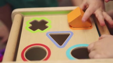 Küçük bebekler ahşap eğitim oyunu oynuyorlar. Farklı blok şekilli oyuncaklar. 