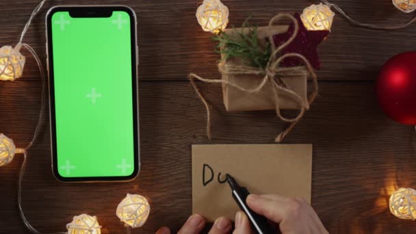 Karácsonyi adomány koncepció: kézírás ajándék kártya és zöld képernyős okostelefon — Stock videók