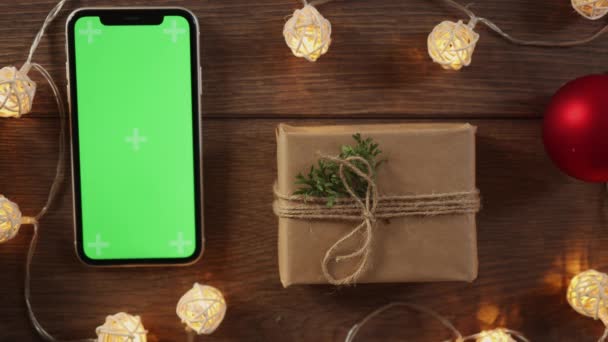 Упаковка саморобної упаковки різдвяний подарунковий смартфон зелений екран на дерев'яному столі — стокове відео