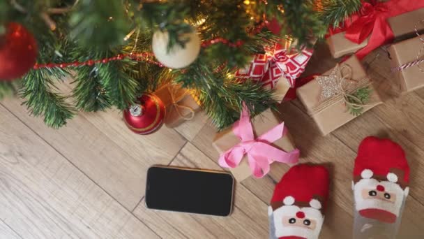 Fundo de Natal com smartphone meias engraçadas e espaço de cópia no chão de madeira — Vídeo de Stock