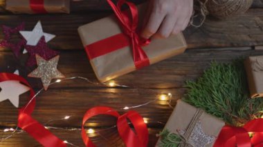 Noel hediyelerini paketleyen kadın elleri kırmızı kurdele bağlayan el sanatları kağıdı