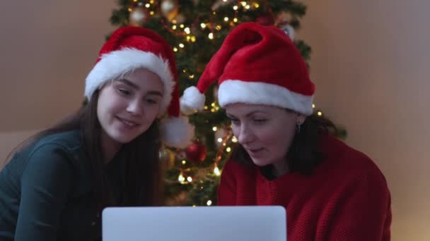 Dwie kobiety czerwony Santa kapelusze rozmowy rozmowy wideo za pomocą laptopa Boże Narodzenie nowy rok — Wideo stockowe