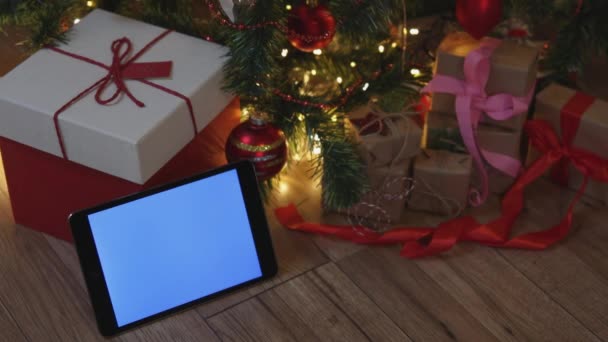 Navidad rojo artesanía cajas de regalo y tableta pantalla mockup azul bajo el abeto — Vídeo de stock