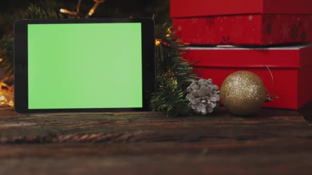 Christmas background red gift box tablet gadget green screen wooden table lights — Stock Video