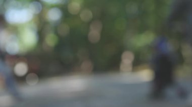 Bulanık yeşil halk parkı, ağaçlar gri yollar, bokeh insanlar yürür.