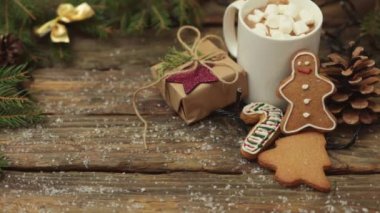 Beyaz fincan kakao, marşmelov, ahşap masada zencefilli kurabiye, hediye kutusu.