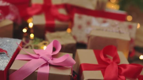 Muchos regalos de Navidad artesanía cajas de papel lazos rojos lazo abeto árbol luces — Vídeos de Stock