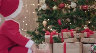 Noel Baba kostümlü bebek köknar ağacının süslediği hediye kutularında oturuyor. 