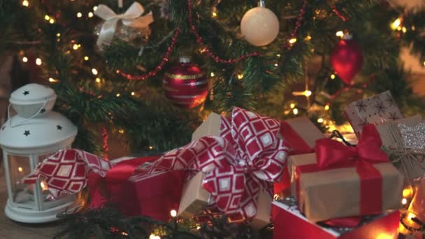 Muchos regalos de Navidad artesanía cajas de papel lazos rojos lazo abeto árbol luces — Vídeo de stock
