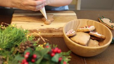 Anne ve çocuk birlikte yemek pişiriyor Noel kurabiyeleri süslüyor, krema parlatıyorlar. 