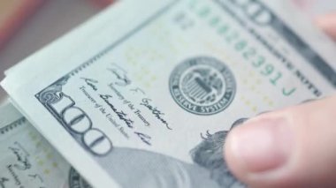 Kadın eli 100 dolarlık banknotları sayıyor. 