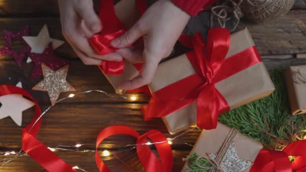 Female hands wrapping Christmas presents gift craft paper tying red ribbon bow — Stock Footage Female hands wrapping Christmas presents gift craft paper tying red ribbon bow Video Clip