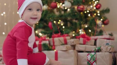 Noel Baba kostümlü bebek köknar ağacının süslediği hediye kutularında oturuyor. 