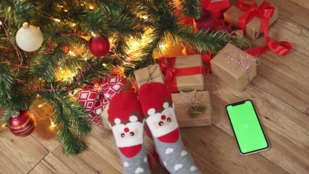 クリスマスの背景とともにスマートフォンの緑の画面モックアップchromakey面白い靴下 — ストック動画