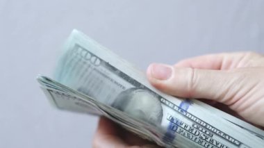 Açık gri arka planda 100 dolarlık banknotları karıştırma